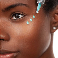 Cosmedix Opti Crystal Liquid Crystal Eye Serum in a light blue squeeze tube on model