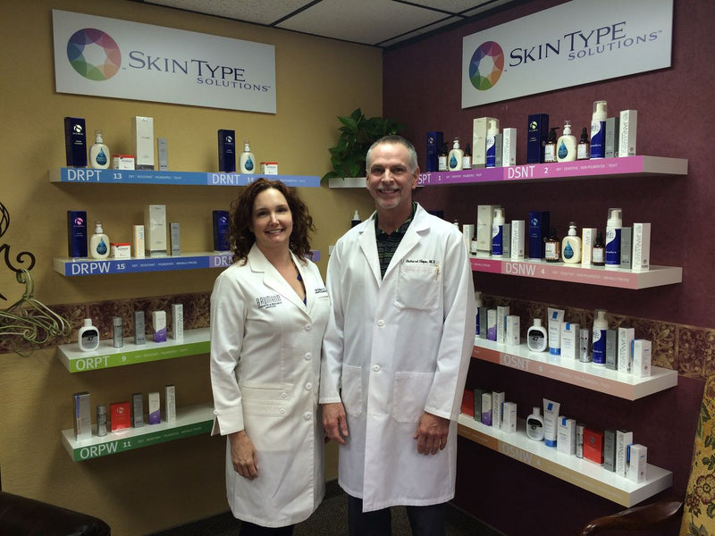Dr. Leslie Baumann and Dr. Richard Hope in front of a Skin Type Solutions product wall at his Lubbock, Texas practice